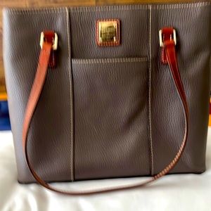 A stylish Dooney&Burke handbag In Brown,with many pockets inside and 2 outside.